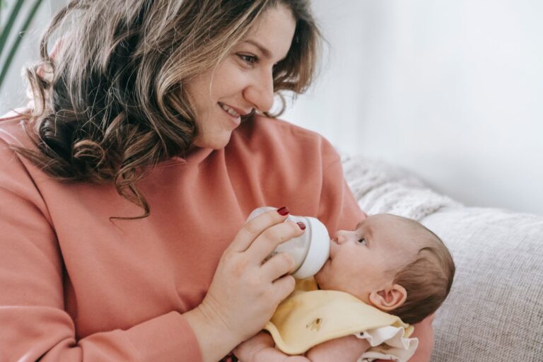 Babyflasche mit Sauger steht neben sauberem Fläschchenzubehör auf der Küchenarbeitsplatte