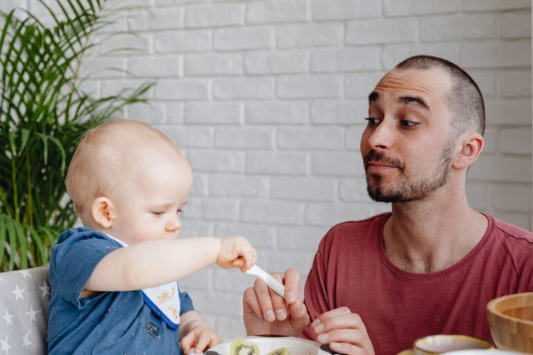 Baby sitzt im Hochstuhl und probiert erste feste Nahrung