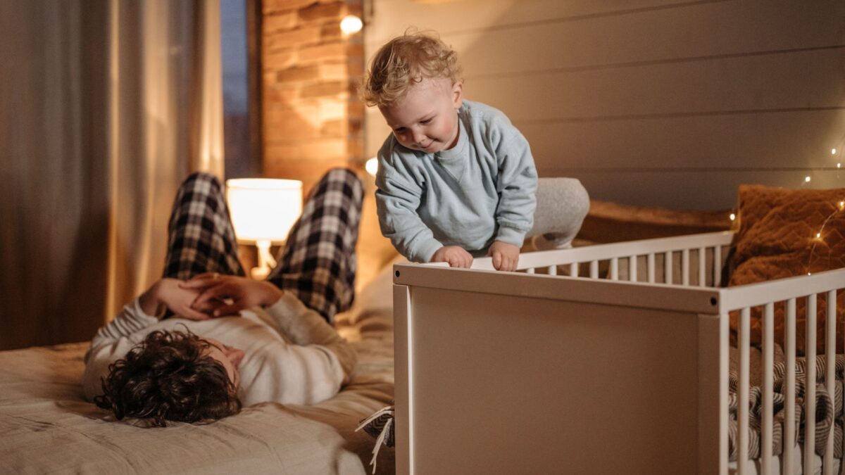 Helles Babybett mit fester Matratze und Schlafsack im Schlafzimmer der Eltern