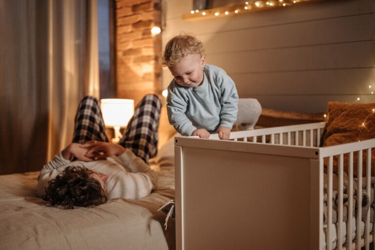 Helles Babybett mit fester Matratze und Schlafsack im Schlafzimmer der Eltern